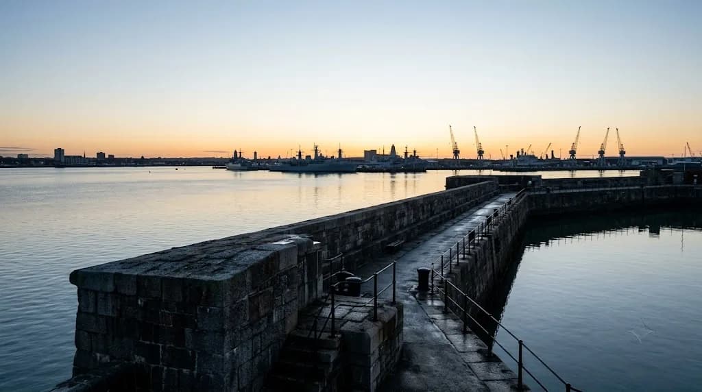 Portsmouth Harbour at early morning with naval vessel silhouettes and harbour wall, representing Aristral's digital marketing work for Portsmouth defence and maritime businesses